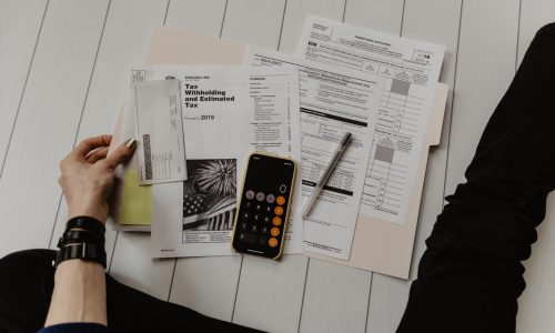 Photo by Kelly Sikkema person holding paper near pen and calculator